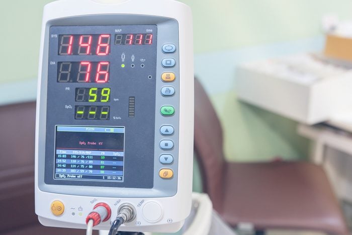 A Hospital Vital Sign Monitor on Trolley with Blood Pressure Cuff and Thermometer on hospital background.