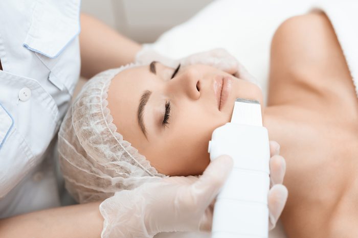 Esthetician or dermatologist applying medical device to woman's face