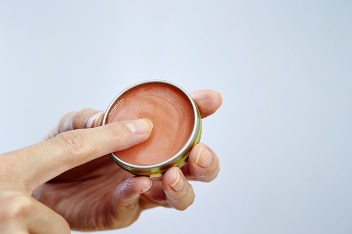hands holding a tin of Lip balm 