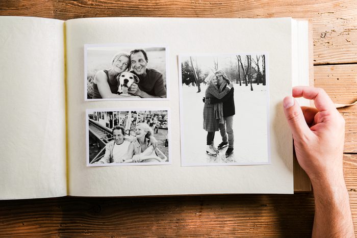 Hand holding photo album with pictures of senior couple. Studio 