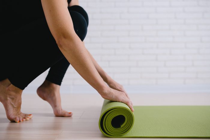 Woman rolling her green mat after a yoga class