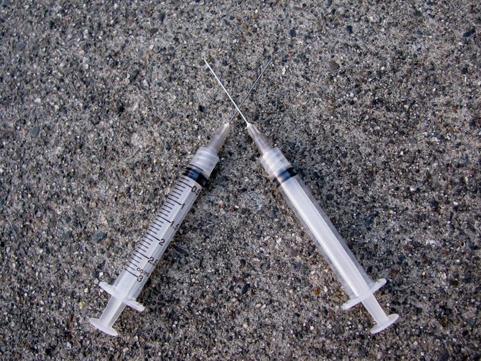 Two crossed syringes on concrete floor