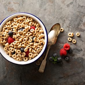 Healthy cold cereal with raspberry and blueberry in a bowl, quick breakfast or snack overhead shot