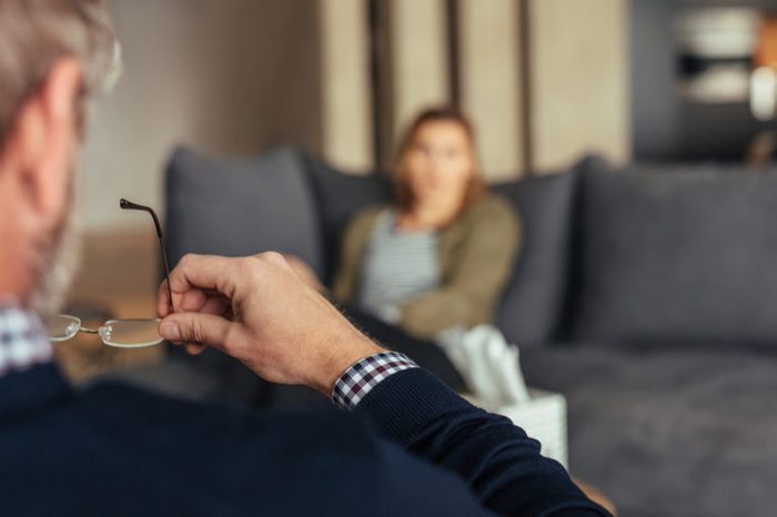 Hands of psychologist holding glasses and listening to woman in trouble during therapy session. Psychotherapist understanding problems of a woman patient.