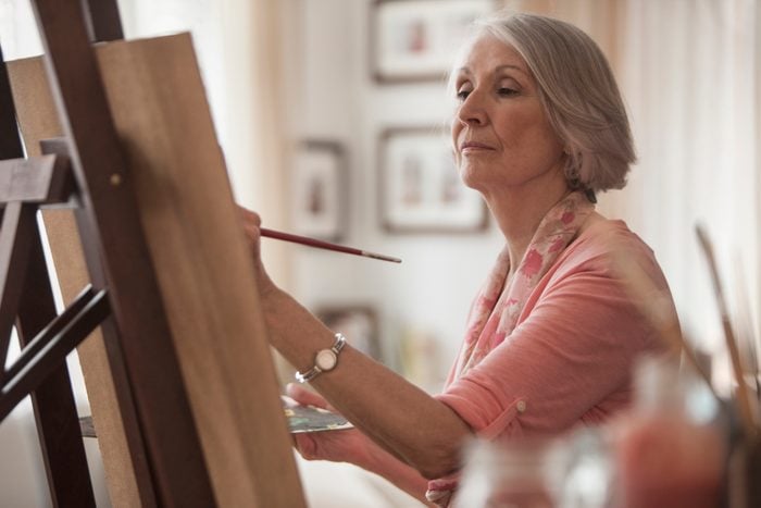 senior woman painting on canvas