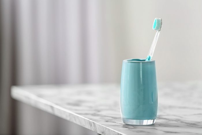 Cup with toothbrush on table. Dental care