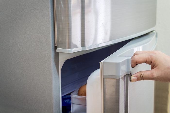 La mano di una donna sta aprendo la porta di un frigorifero