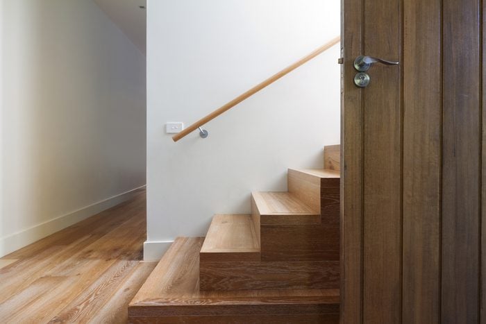 Escadaria moderna de madeira de carvalho ao lado da porta da frente em casa contemporânea horizontal