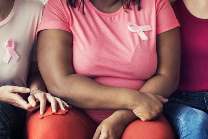 women sitting wearing t-shirts with the pink breast cancer ribbon