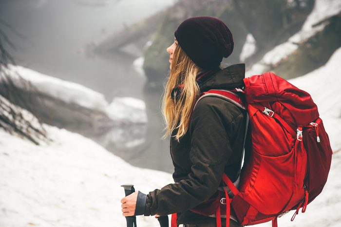 Woman Traveler with backpack hiking Travel Lifestyle adventure concept active vacations outdoor snow forest on background