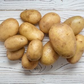 Young potatoes on white wooden background, view from above