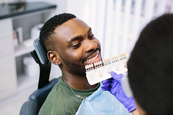 dentist holding up veneers to man's mouth