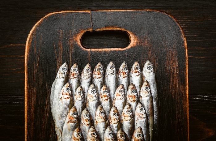 свежая сырая рыба, анчоусы и килька на деревянной поверхности