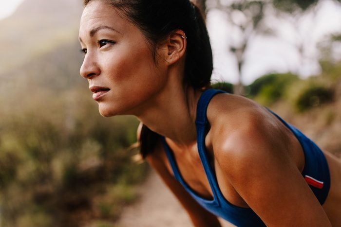 Close up of young asian woman resting after workout and looking away. Female runner in sportswear taking a break.