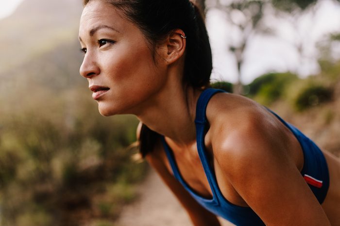 Close up of young asian woman resting after workout and looking away. Female runner in sportswear taking a break.