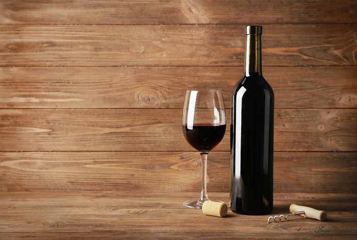 Wine bottle and glass of red wine on wooden background