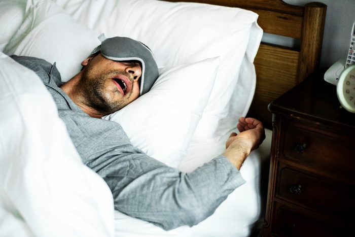 A man sleeping on a bed with sleep mask on