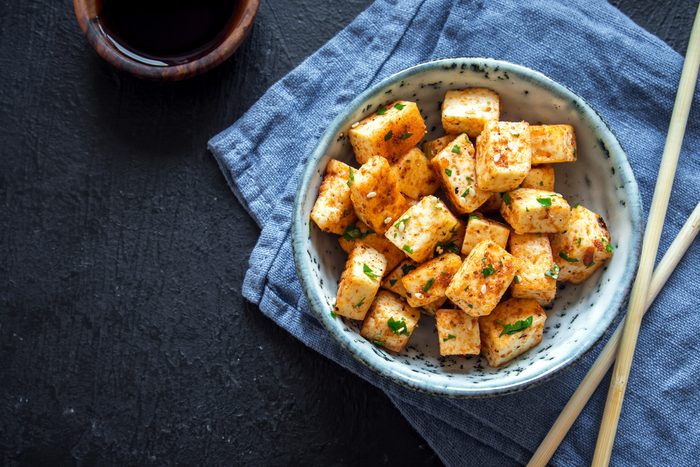 Stir Fried Tofu in a bowl with sesame and greens. Homemade healthy vegan asian meal - fried tofu.