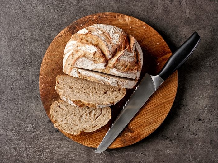 freshly baked bread and knife on dark gray table, top view