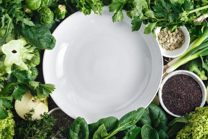 plate surrounded by green vegetables and seeds
