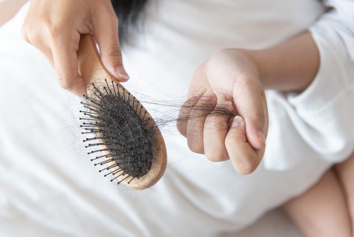 woman show her brush for presentation hair loss problem and looking at her hair