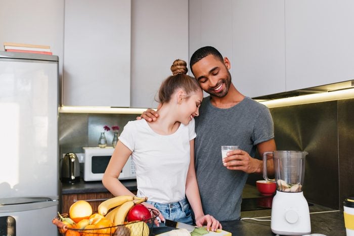 A young couple making breakfast in the kitchen. Men and women in T-shirts embracing each other, cook together, the couple hugging with happy faces and a smile on their faces. family life.