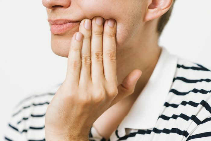 man holding side of mouth with painful jaw