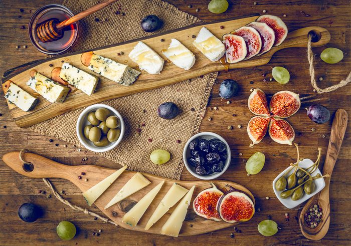 platter of italian cheeses with figs, olives, grapes and honey toned