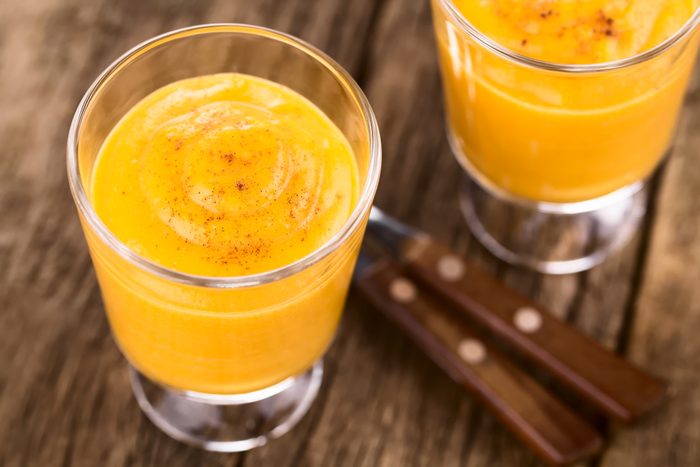 Fresh homemade pumpkin mousse or cream in glasses sprinkled with cinnamon, photographed on rustic wood (Selective Focus, Focus one third into the dessert)