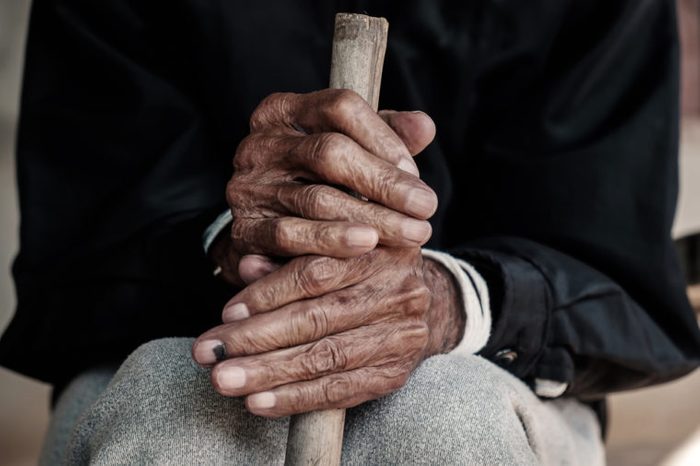hand of a old man begging for money because of the hunger holding a cane.vintage tone