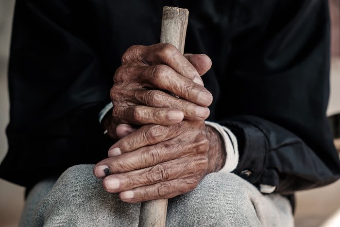 hand of a old man begging for money because of the hunger holding a cane.vintage tone