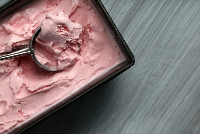 Homemade ice cream in frozen metallic container on wooden background
