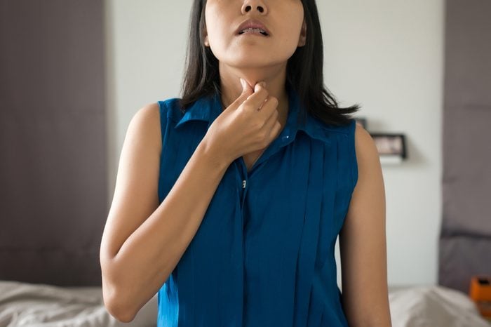 Woman with touching her neck with a sore throat.