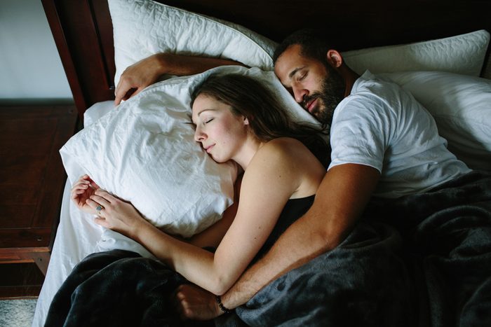 Black and white couple sleeping and holding each other in bed