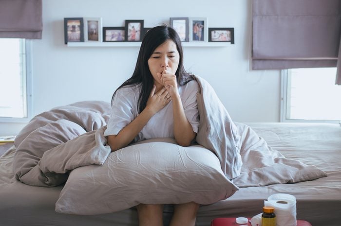 Young asian woman coughing and sitting on her bed,Concept of health