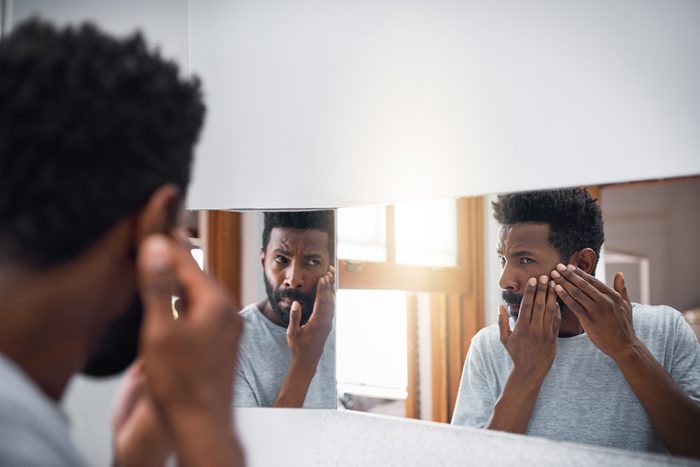 man looking at face in mirror