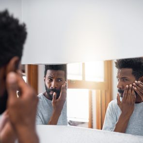 man looking at face in mirror