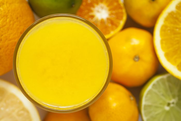 glass of orange juice surrounded by citrus fruits