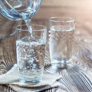Glass of water on a wooden table. Water was poured into the beaker. Selective focus. Shallow DOF. With lighting effects. With copy space