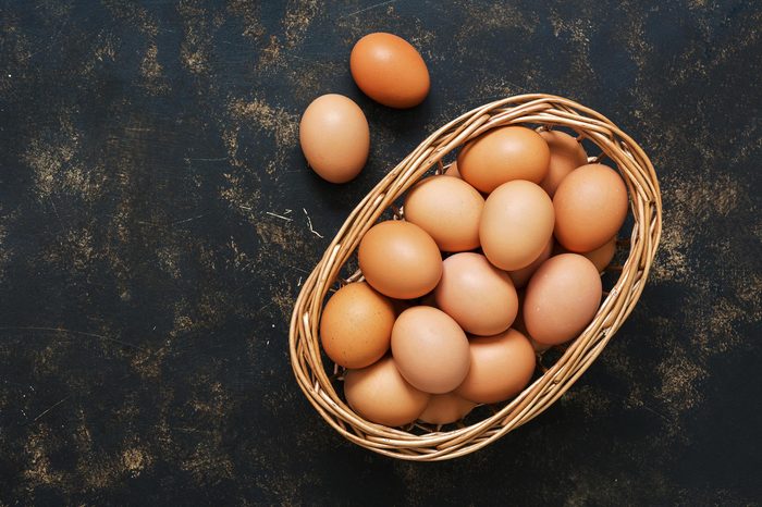 Brown eggs in a basket on an old dark surface. Top view, space for text