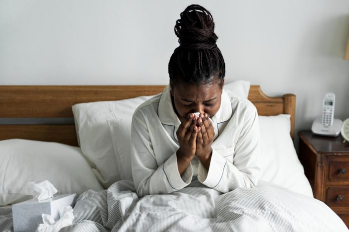 woman in bed blowing her nose