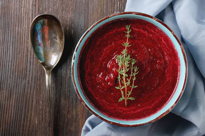 Traditional beetroot soup in a blue plate with Temyan. Dark wood background. Light fabric. free space text. Top view