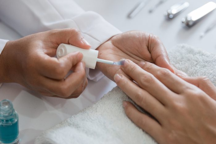 Beautician using a nail polish giving customer service a manicure at salon