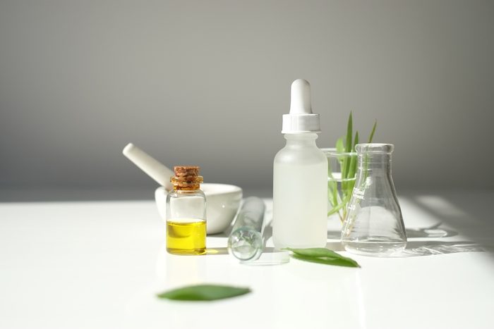 blank cosmetic white serum dropper bottle containers with herbal ingredient and laboratory glass ware. package for branding .Natural organic beauty skincare product concept. alternative medicine.