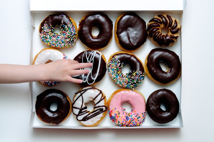 Picture of doughnut box with a child's hand grabbing a doughnut