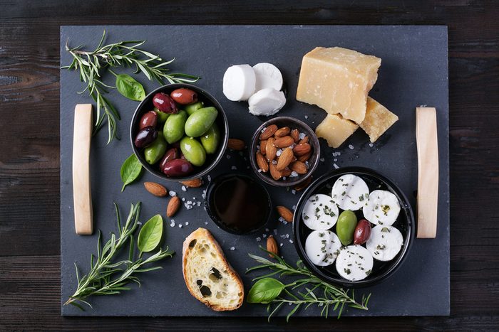 A set of Italian appetizers: salami and goat cheese, served with bread, olives, olive oil and wine decorated with napkin. Top View
