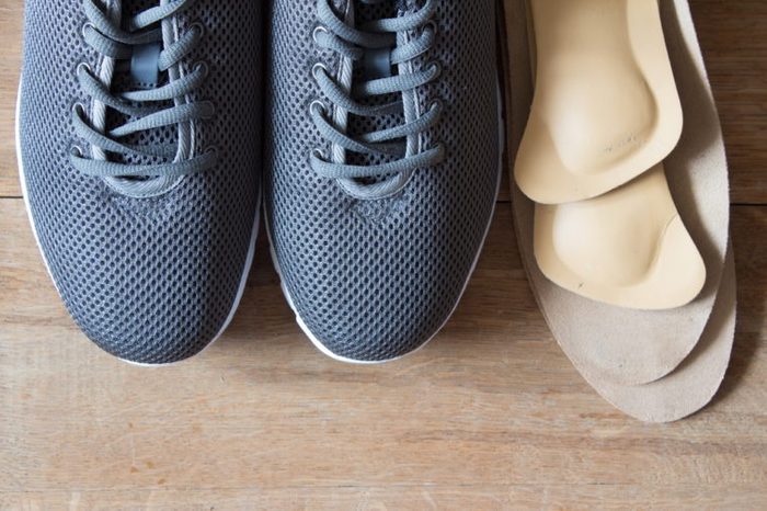 Gray sport shoes with orthopedic insoles. Wooden background.
