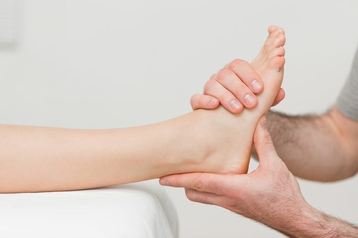 Hands of an osteopath massaging a foot in a room