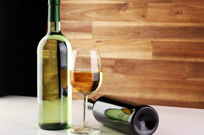 Bottle and glass of wine on white table