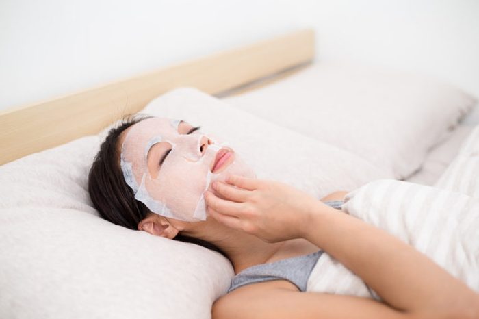 Woman use of the paper mask ans lay on the bed